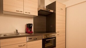 A modern kitchen with light wood cabinetry, stainless steel appliances, and a built-in oven. - Sonnenhof by Interhome (Umhausen)