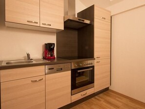 Ett modernt kök med ljusa träskåp, rostfria vitvaror och en inbyggd ugn.
