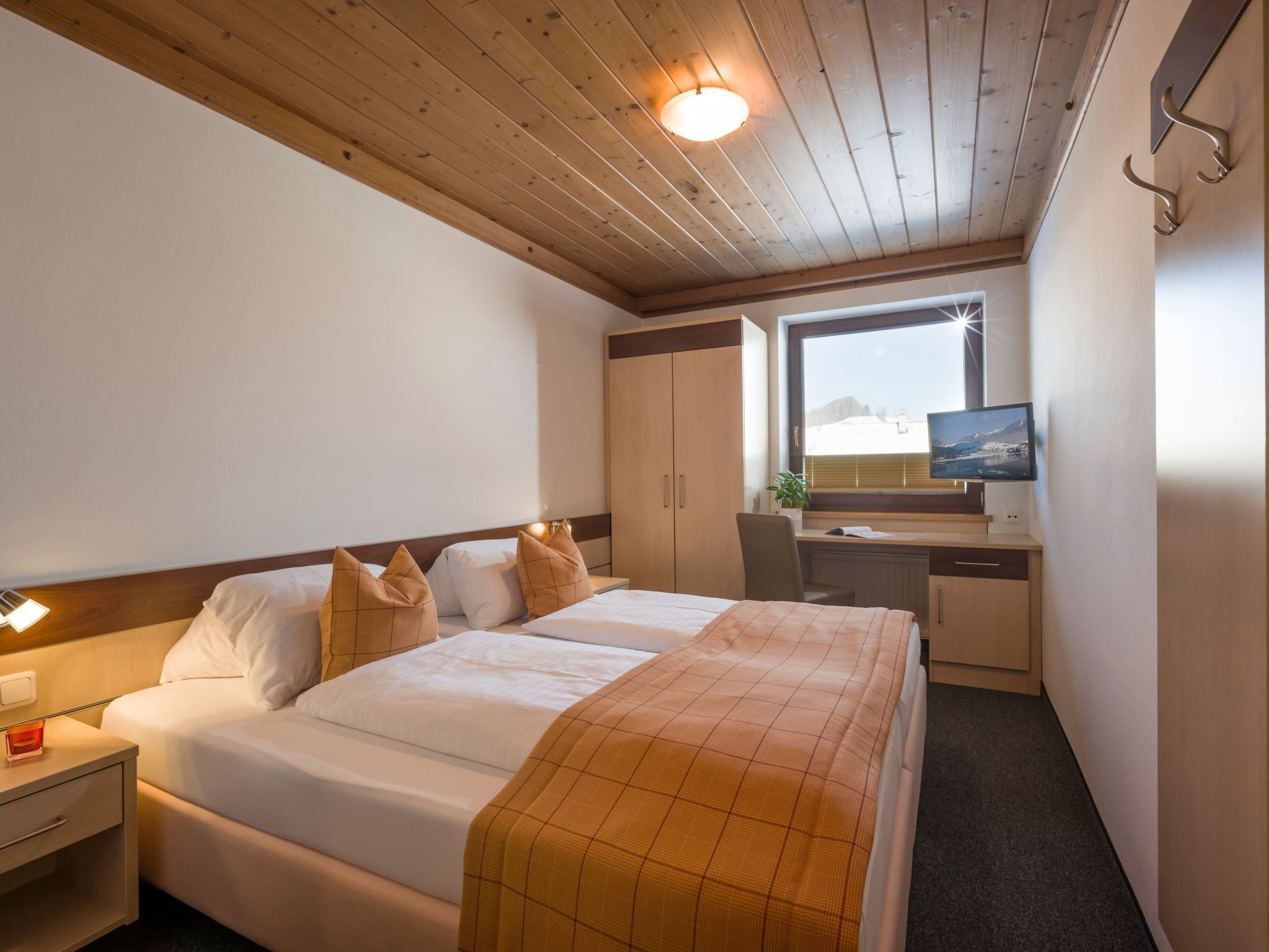 Camera d'albergo con un letto grande, una scrivania con un computer e una finestra vista su un paesaggio innevato.