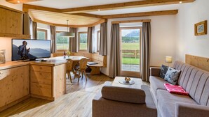 Un acogedor interior de cabaña con vigas de madera, una zona de comedor, un sofá y un televisor.