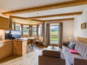Ein gemütliches Blockhaus-Interieur mit Holzbalken, einem Essbereich, einer Couch und einem Fernseher.