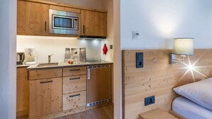 Una cocina compacta con armarios de madera, microondas, cafetera y un pequeño comedor con mesa y sillas.