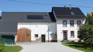 Une maison à deux étages avec une allée pavée, une porte de garage en bois et un petit jardin.
