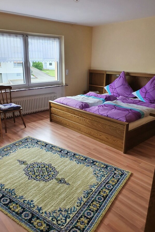 Een slaapkamer met een bed, een stoel, een raam met uitzicht en een kamerbreed tapijt.