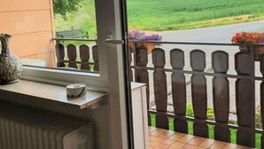 Ett rum med utsikt över en grön äng genom ett fönster med en dekorativ gardin.