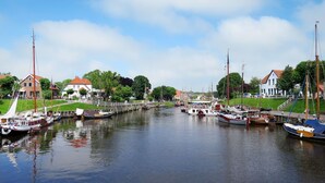 A canal with boats docked on both sides, surrounded by buildings and greenery. - Martina 3 by Interhome (Friederikensiel)