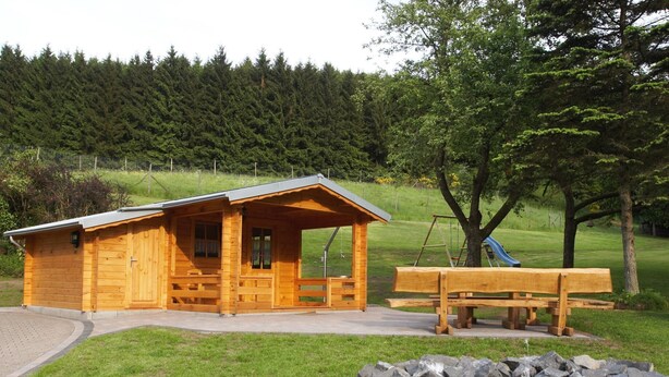 A wooden cabin with a porch, a picnic table, and a rock garden. - für 11 Personen und 1 Kind by Interhome (Birresborn)