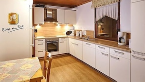 A compact kitchen with white cabinets, a wooden ceiling, and a dining area with a table and chairs. - für 11 Personen und 1 Kind by Interhome (Birresborn)