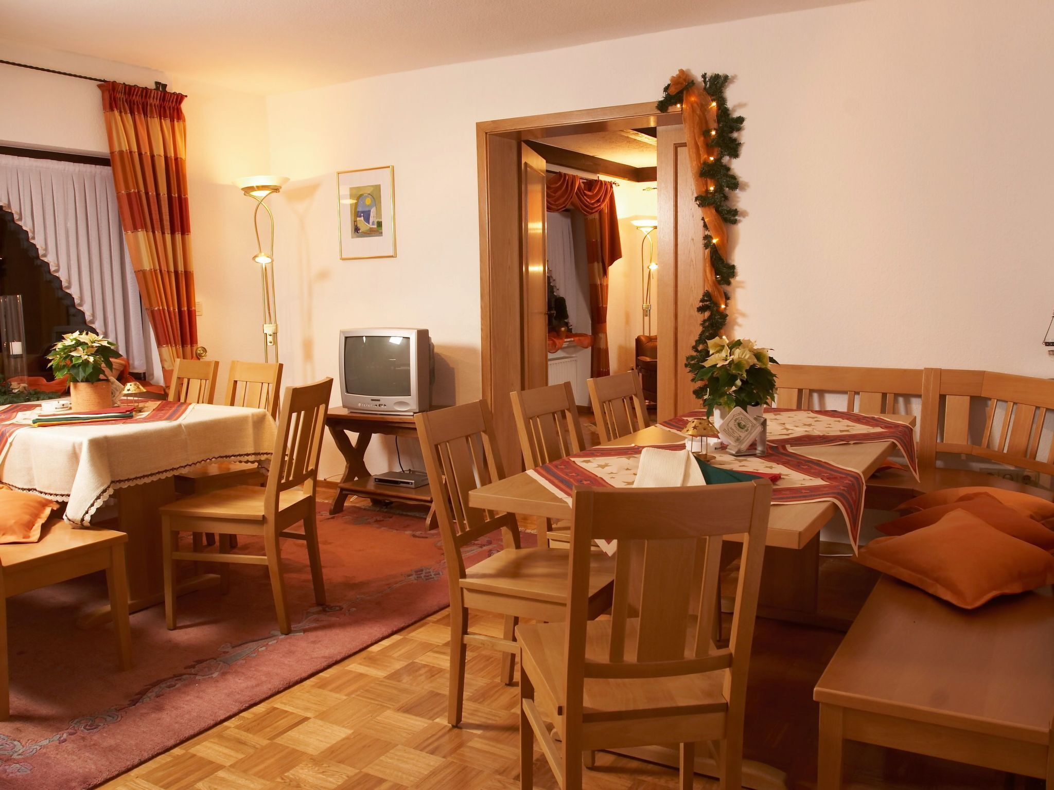 Ein Essbereich mit Holztischen, einem Fernseher und einer Weihnachtsdeko.