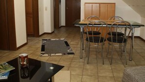 Un comedor con una mesa de madera y cuatro sillas de metal, una mesa baja negra y una revista.