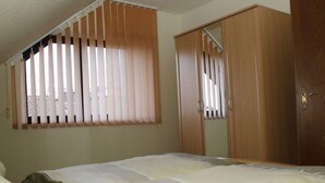 Un dormitorio con cama, armario y ventana con persianas.