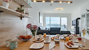 Uma cozinha moderna com uma mesa de jantar posta para o café da manhã, uma janela grande com vista e uma TV fixada na parede.