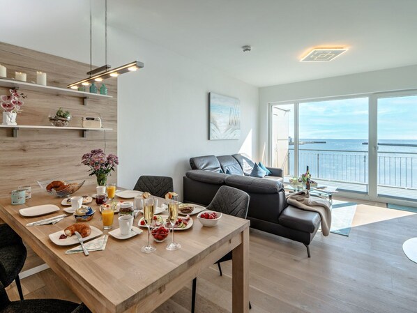 Un salon moderne comprenant un coin repas, un canapé et un balcon avec vue sur la mer.