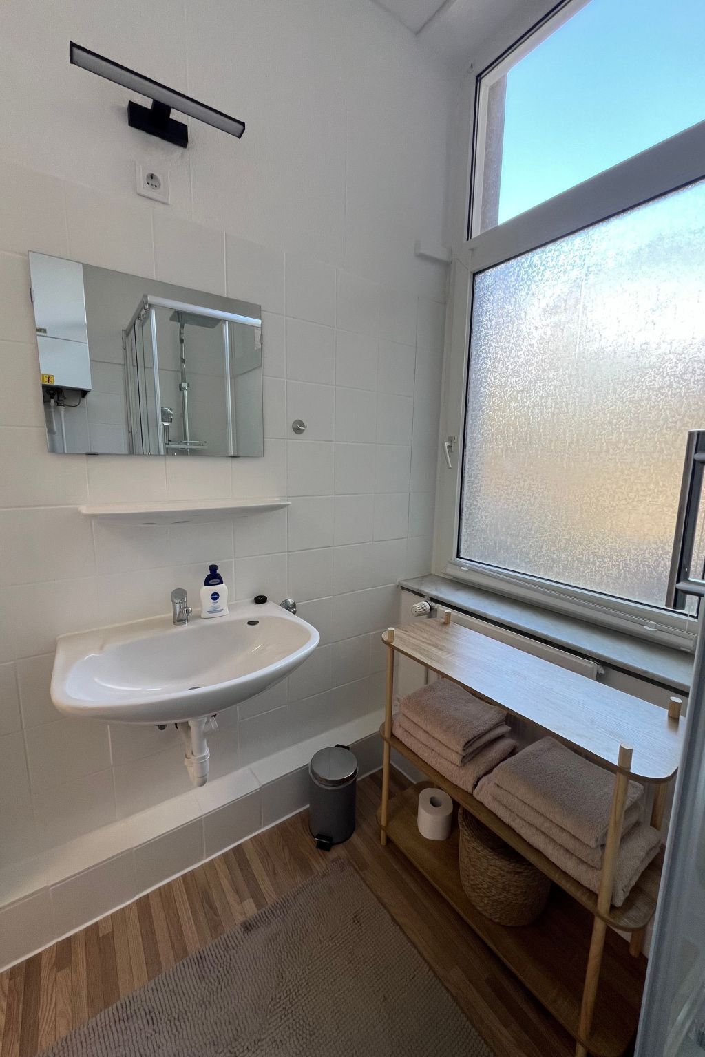 A bathroom with a white sink, mirror, and window.