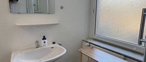 A bathroom with a white sink, mirror, and window.