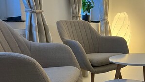 Una sala de estar moderna con dos sillones color beige, una mesita redonda y una planta en maceta.