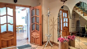 Un ingresso spazioso con porte in legno, un attaccapanni e uno specchio che riflette la scala.