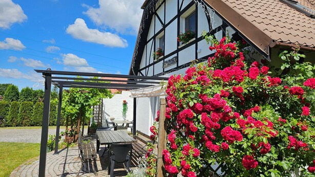 Una casa tradizionale con struttura a graticcio, un patio con giardino, posti a sedere all'aperto e un pergolato.