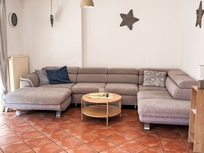 A modern living room with a sectional sofa, a round wooden coffee table, and decorative wall art. - mit Garten und Stellplatz by Interhome (Großenaspe)