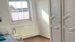 Ein Schlafzimmer mit Bett, Fenster, Heizkörper und Kleiderschrank.