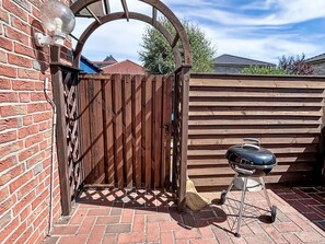 A wooden gate leading to a brick patio with a barbecue grill. - mit Garten und Stellplatz by Interhome (Großenaspe)