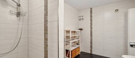 A modern bathroom with a shower, toilet, and storage shelves.