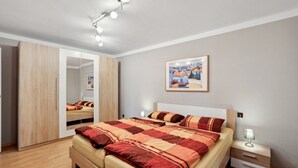 Une chambre à coucher moderne avec un grand lit, une table de chevet, un miroir et un tableau accroché au mur.