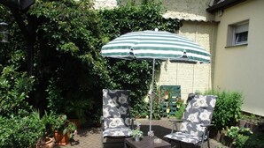 An outdoor patio with two chairs and a table, an umbrella, and potted plants. - Appartement in Törten by Interhome (Törten)