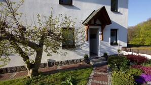 Una casa moderna con facciata bianca, un portico in legno e un vialetto in mattoni che conduce all'ingresso.