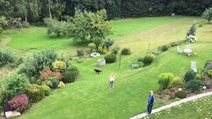 Un giardino curato con prato, siepi varie e un vialetto in pietra.