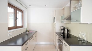 A modern kitchen with a window, stainless steel appliances, and a tiled floor. - Bohemia 4 in Gargellen by Interhome (Gargellen)