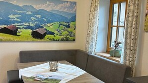 Un angolo accogliente con un tavolo di legno, una panca e una finestra con tende.