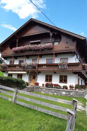 A traditional wooden house with a balcony, stone steps, and flower pots. - Wimmerhof - Appartement Bergsonne by Interhome (Breitenbach am Inn)