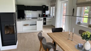 A modern kitchen with white cabinetry, a built-in oven, and a dining area with a wooden table and chairs. - Vacation home Lotte by Interhome (Groß Schoritz)