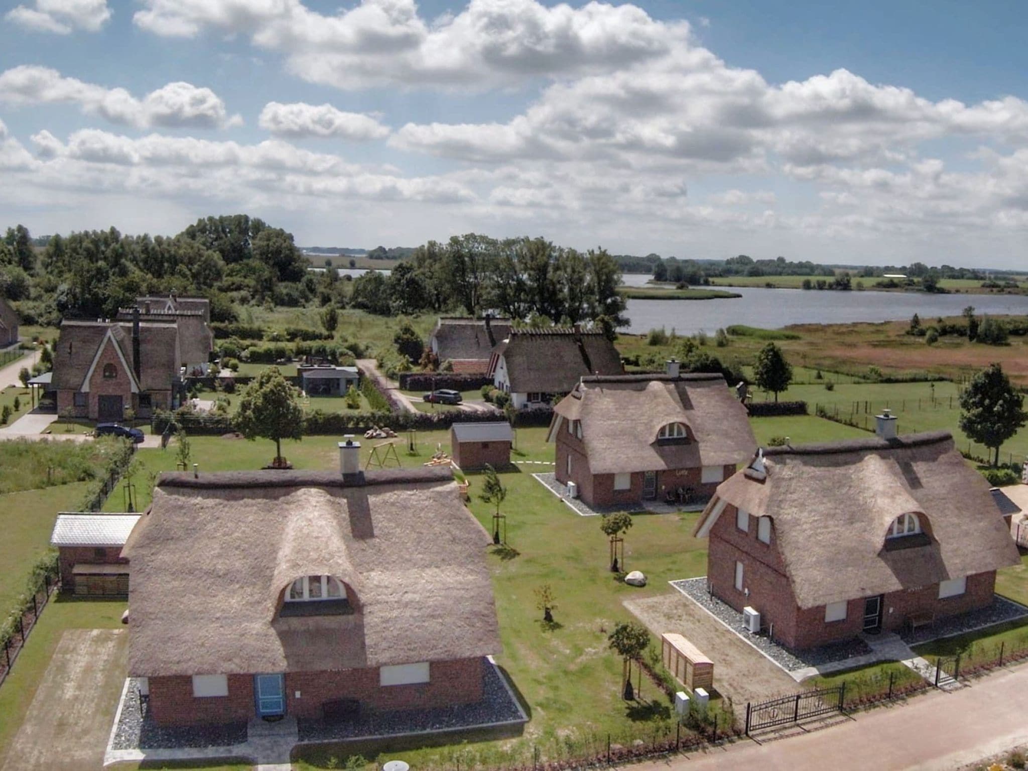 Un pueblo rural con casas de techo de paja, un lago y una iglesia.