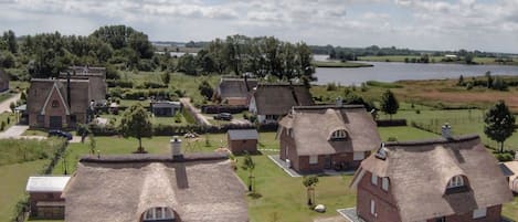 Un pueblo rural con casas de techo de paja, un lago y una iglesia.