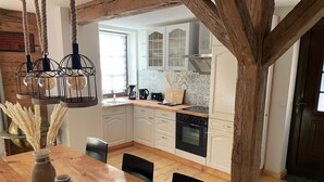 Een moderne keuken met witte kastjes, een houten eettafel en een hanglamp.
