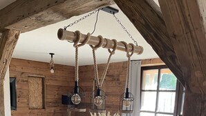 Een houten eettafel met zwarte stoelen, een vaas met gedroogde planten en hangende lantaarns.
