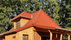 Een houten huis met een rood dak, een bakstenen gedeelte en een grindpad.