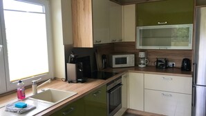 Una cocina moderna con horno empotrado, microondas y cafetera.