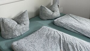 Un dormitorio moderno con un cuadro abstracto grande, dos camas estampadas y un diseño minimalista.
