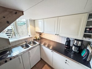 A kitchen with white cabinets, a black countertop, a sink, a stove, and a coffee maker.