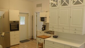 A compact kitchen with white cabinets, a microwave, an oven, and a wooden countertop. - Wunderschönes Cottage "Traum von Wald und Meer" by Interhome (Stenungsund)