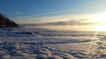 Een besneeuwd landschap met een heldere lucht en een ondergaande of opkomende zon.