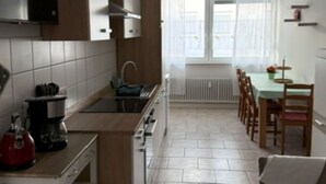 A modern kitchen with a central island, a dining area with a table and chairs, and a view of the outside through a window. - Panorama 180° by Interhome (Kitzingen)