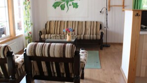 A living room with striped sofas, a wooden coffee table, and a green rug.