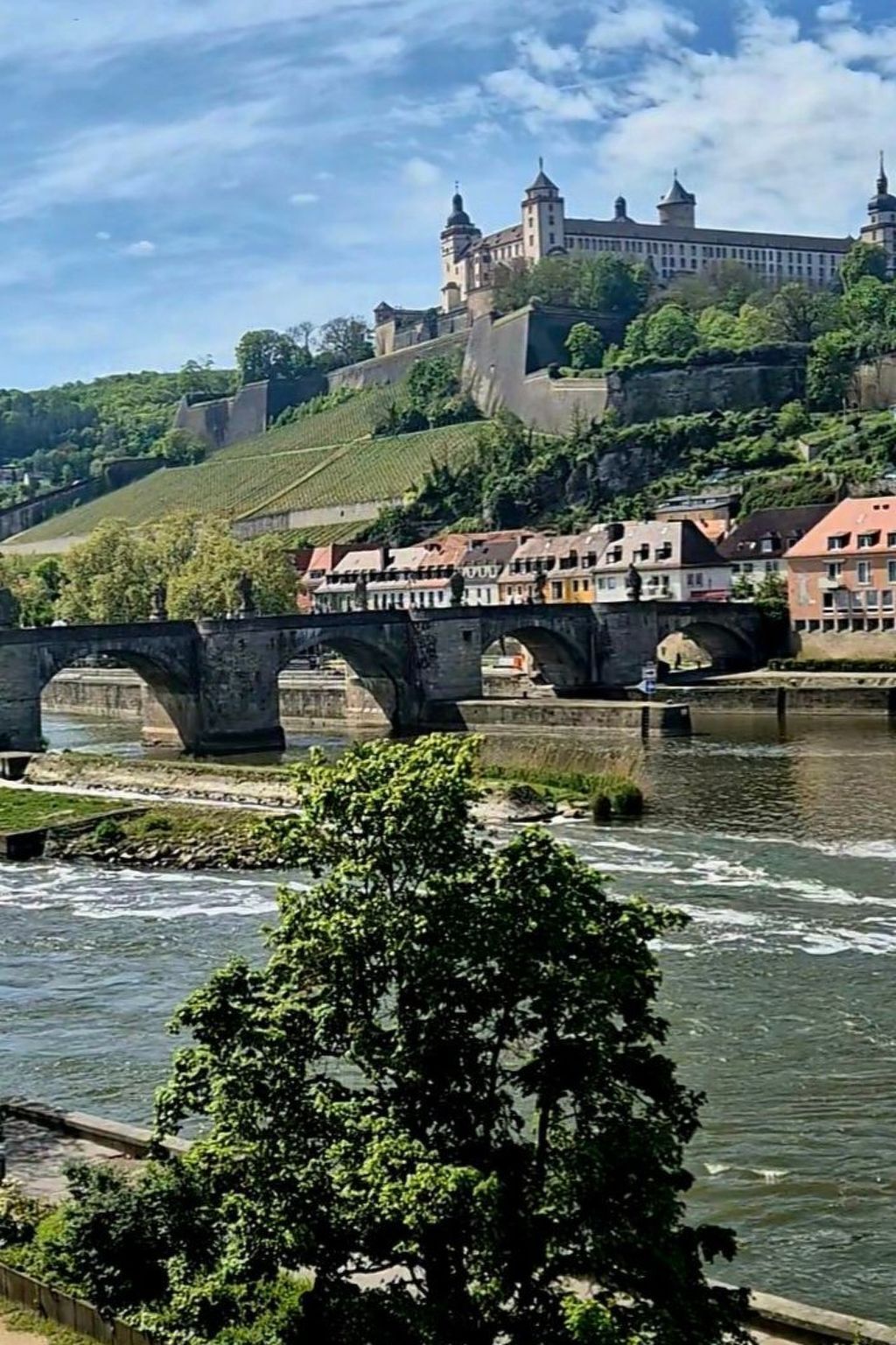 Un puente histórico con arcos de piedra sobre un río, que conduce a un castillo en una colina.