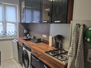 Une cuisine compacte équipée d’un lave-linge, d’une machine à café et d’une cuisinière à gaz.