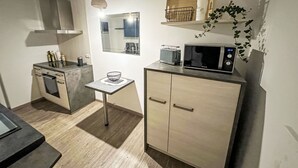 Et kompakt køkken med mikrobølgeovn, et lille bord og et skab.