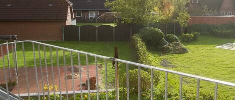 A residential backyard with a fenced area, a small garden, and a house with a sloped roof.